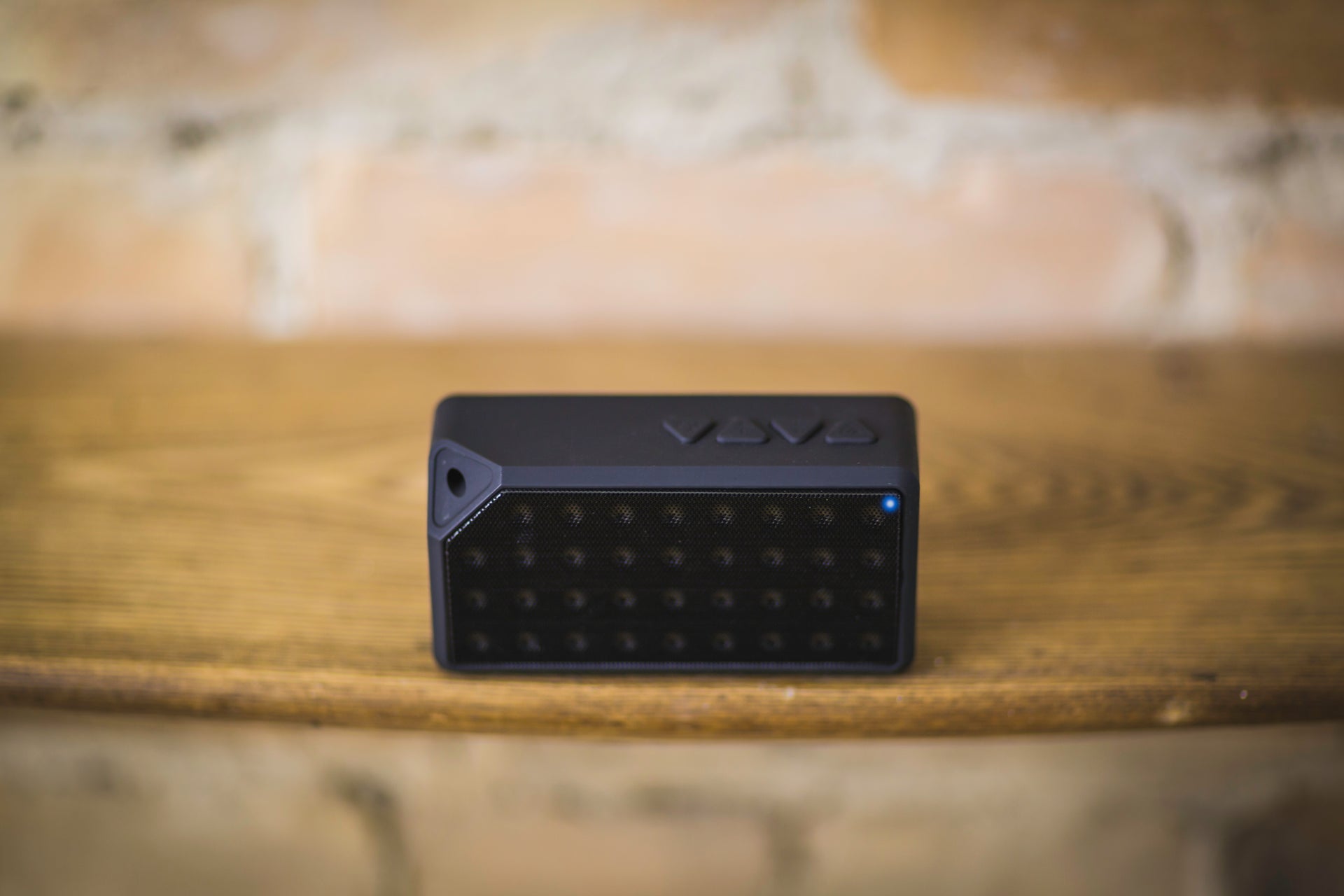 a wireless bluetooth speaker atop a wooden table